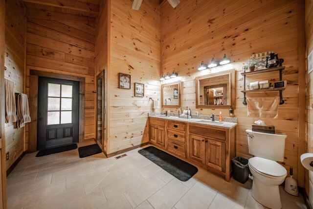 bathroom featuring tile patterned flooring, vanity, and wooden walls