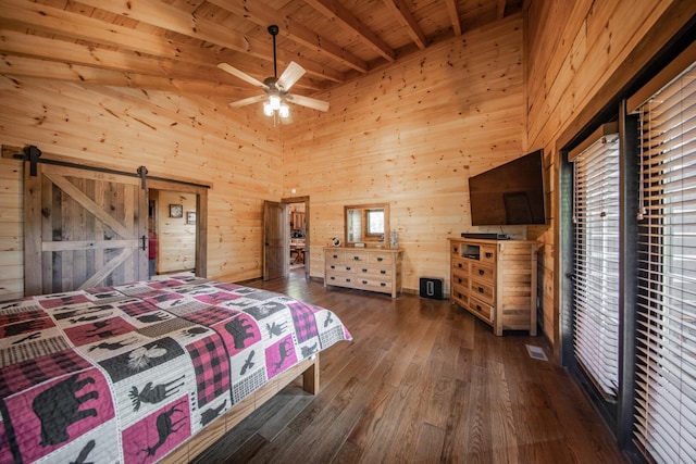 bedroom with ceiling fan, a barn door, beamed ceiling, wooden walls, and wood ceiling