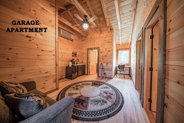 living area with lofted ceiling with beams, wood walls, light wood-type flooring, and wood ceiling