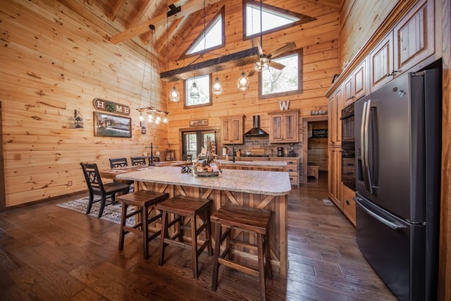 kitchen with high vaulted ceiling, a spacious island, wall chimney range hood, beam ceiling, and stainless steel fridge with ice dispenser