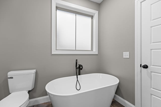 bathroom with a wealth of natural light, a washtub, and toilet