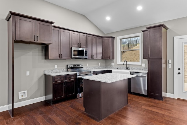 kitchen with appliances with stainless steel finishes, a center island, dark hardwood / wood-style flooring, and vaulted ceiling