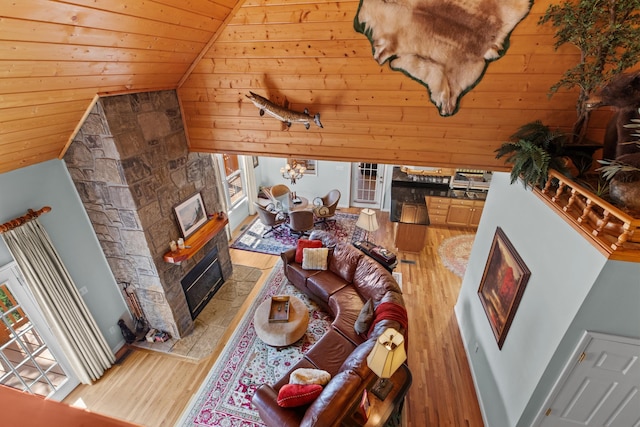 living area with high vaulted ceiling, wooden ceiling, a glass covered fireplace, and wood finished floors