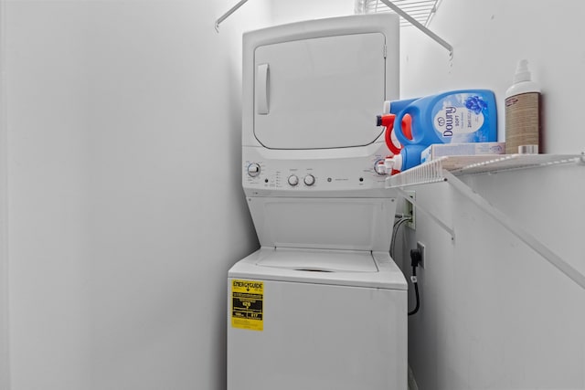 clothes washing area featuring stacked washer and dryer and laundry area