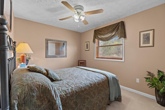 carpeted bedroom featuring baseboards, ceiling fan, and a textured ceiling
