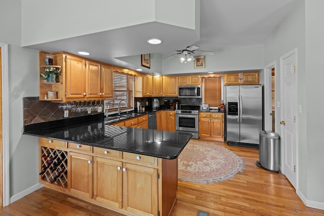 kitchen featuring light wood-style flooring, decorative backsplash, appliances with stainless steel finishes, and a peninsula