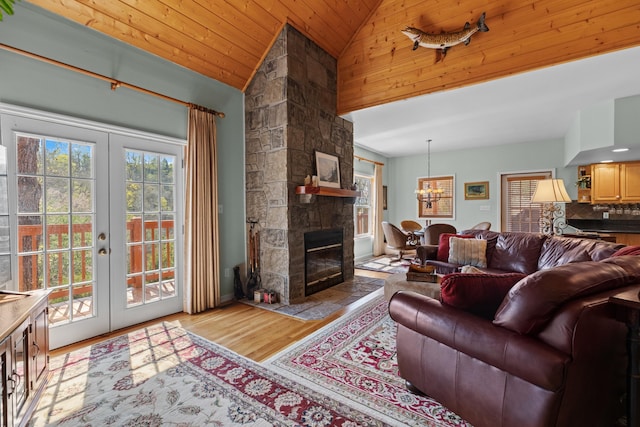 living area featuring french doors, a notable chandelier, a fireplace, and wood finished floors