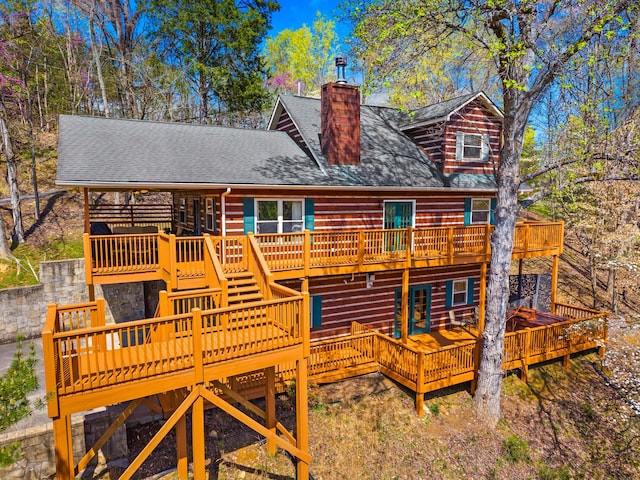 back of house featuring a chimney, a wooden deck, and roof with shingles