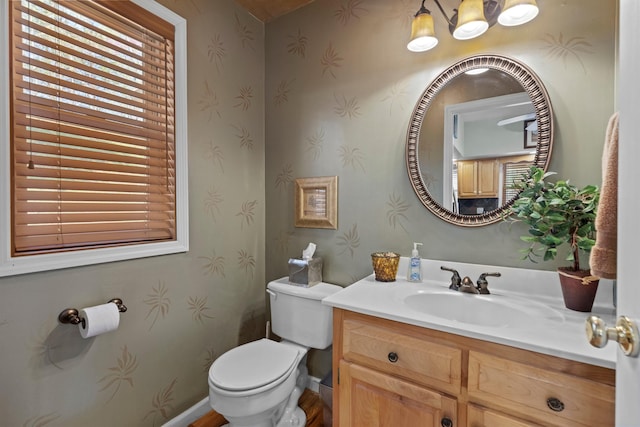 bathroom featuring baseboards, wallpapered walls, toilet, and vanity