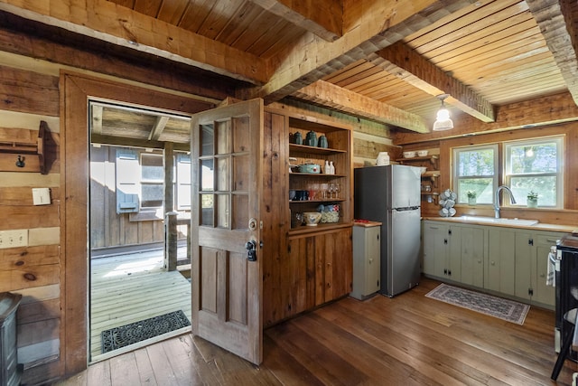 kitchen featuring beam ceiling, stainless steel refrigerator, sink, light hardwood / wood-style flooring, and wooden walls