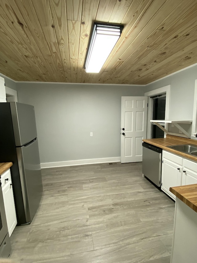 kitchen featuring appliances with stainless steel finishes, sink, white cabinetry, and butcher block counters