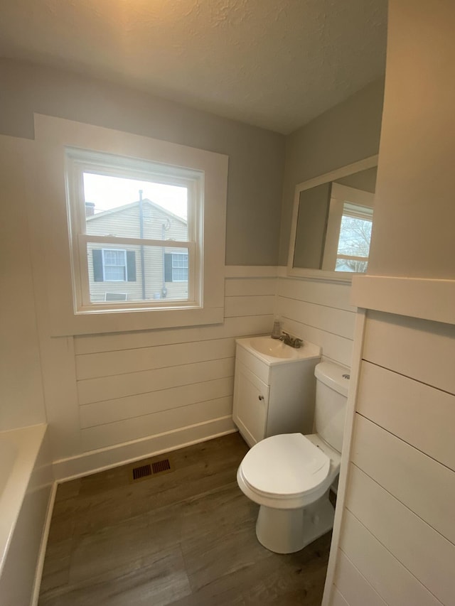 bathroom featuring hardwood / wood-style flooring, a tub to relax in, toilet, a textured ceiling, and vanity