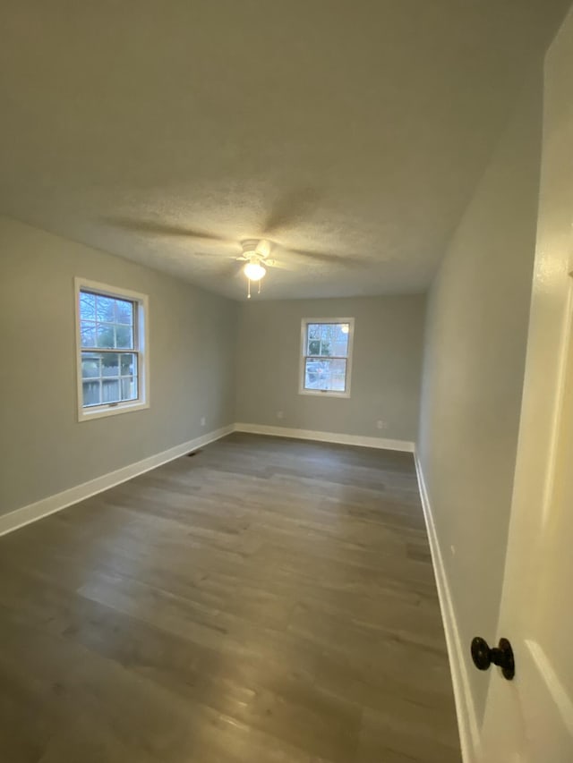 spare room with a textured ceiling, ceiling fan, and dark hardwood / wood-style floors