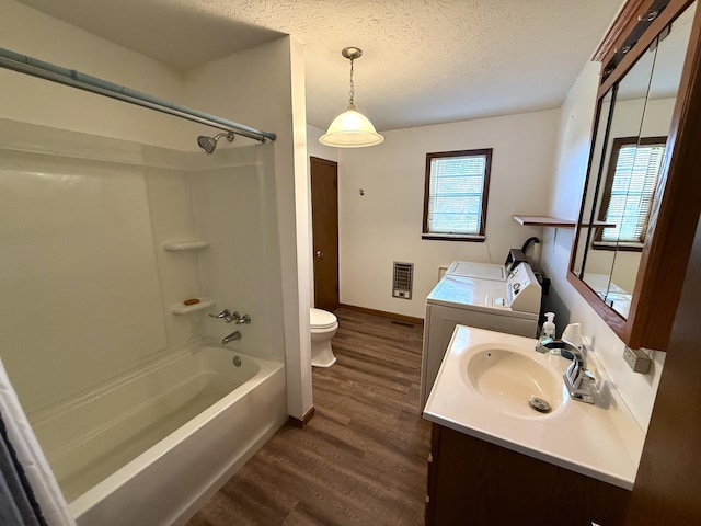 full bathroom featuring a textured ceiling, vanity, shower / bathing tub combination, washing machine and clothes dryer, and hardwood / wood-style floors