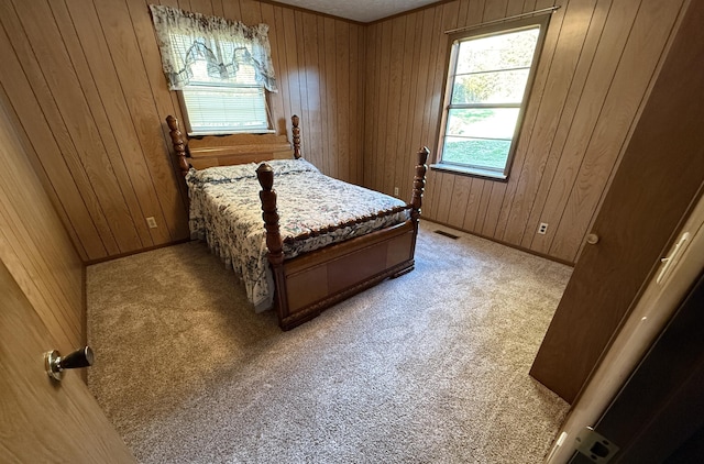 carpeted bedroom with multiple windows and wood walls