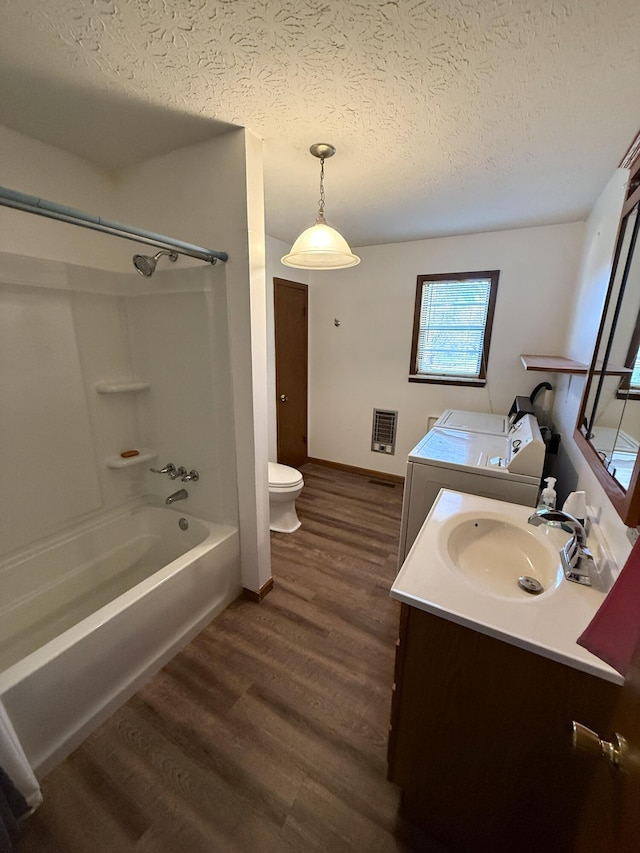 full bathroom featuring hardwood / wood-style floors, a textured ceiling, shower / washtub combination, vanity, and washer and dryer