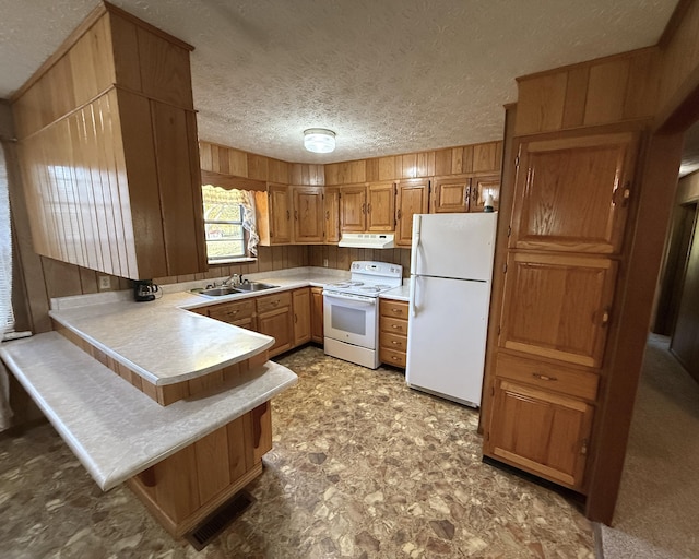 kitchen featuring sink, a kitchen breakfast bar, kitchen peninsula, a textured ceiling, and white appliances