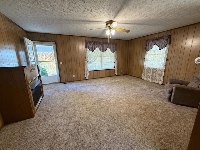 unfurnished living room featuring ceiling fan, plenty of natural light, light carpet, and a textured ceiling