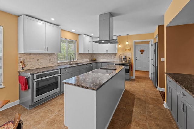 117 Tahlequah Ln, Loudon, TN 37774 - kitchen featuring stainless steel appliances, a sink, island exhaust hood, decorative backsplash, and dark stone counters
