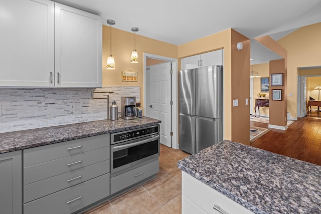 117 Tahlequah Ln, Loudon, TN 37774 - kitchen with appliances with stainless steel finishes, white cabinets, tasteful backsplash, dark stone countertops, and decorative light fixtures