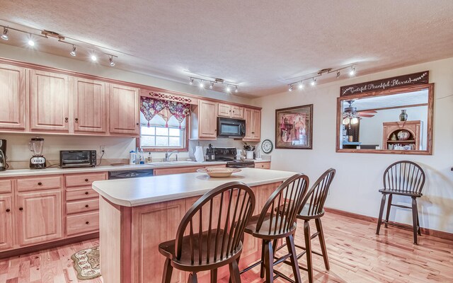 150 Florence Cir, Dandridge, TN 37725 - kitchen with light wood-type flooring, a textured ceiling, a kitchen island, and black appliances
