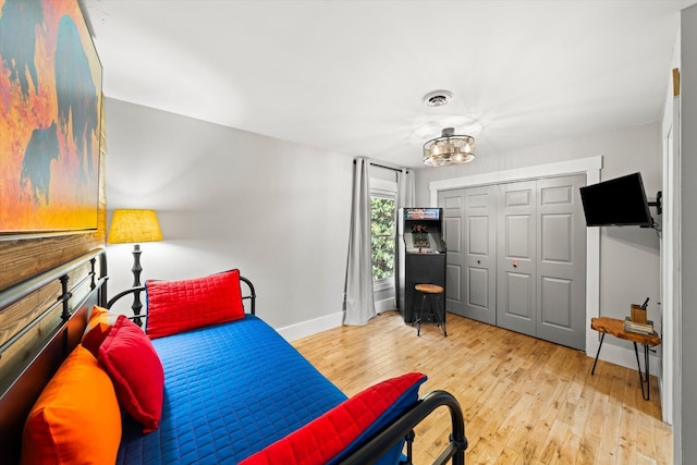 bedroom with a closet, wood-type flooring, visible vents, and baseboards