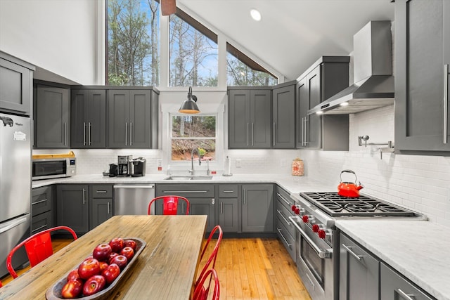 kitchen featuring a sink, wall chimney exhaust hood, light countertops, and stainless steel appliances