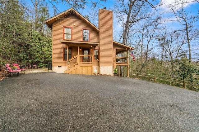 chalet / cabin featuring crawl space, a chimney, and aphalt driveway