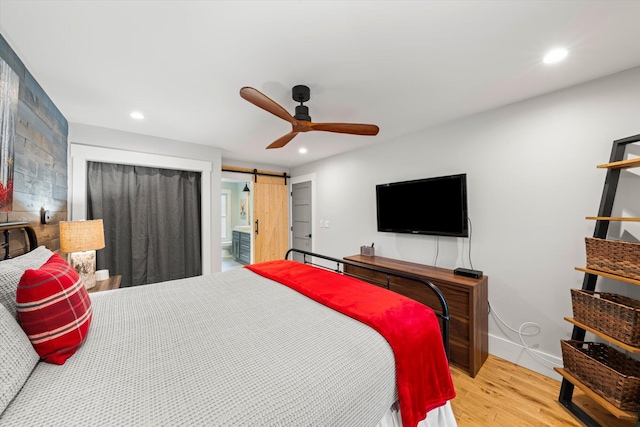 bedroom with recessed lighting, wood finished floors, baseboards, and a barn door