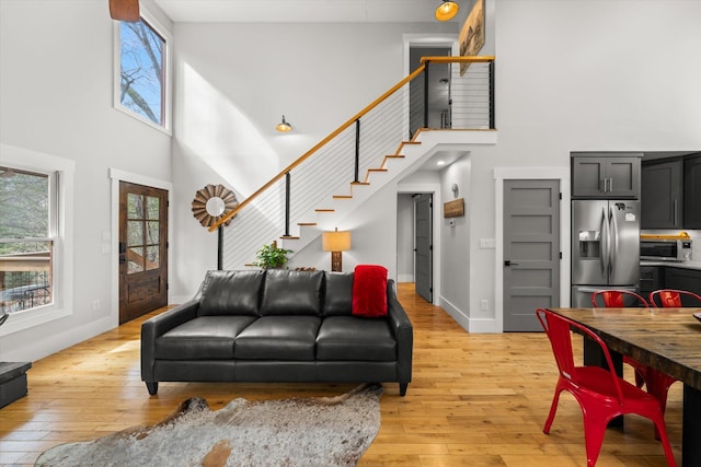 living area with a healthy amount of sunlight, light wood finished floors, stairs, and baseboards