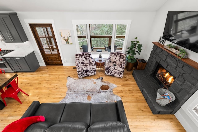 living area with light wood-style floors, a fireplace, and baseboards