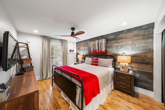 bedroom featuring a ceiling fan, recessed lighting, wood walls, and light wood-style flooring