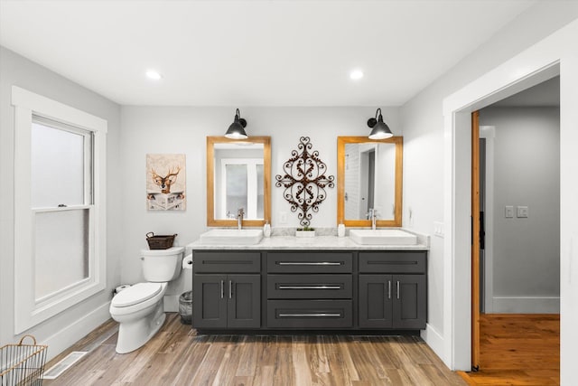 bathroom featuring toilet, visible vents, a sink, and wood finished floors