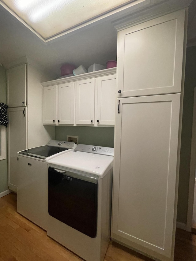 laundry room featuring cabinets, light wood-type flooring, and washing machine and dryer