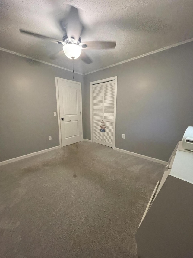 unfurnished bedroom with crown molding, ceiling fan, a textured ceiling, carpet floors, and a closet