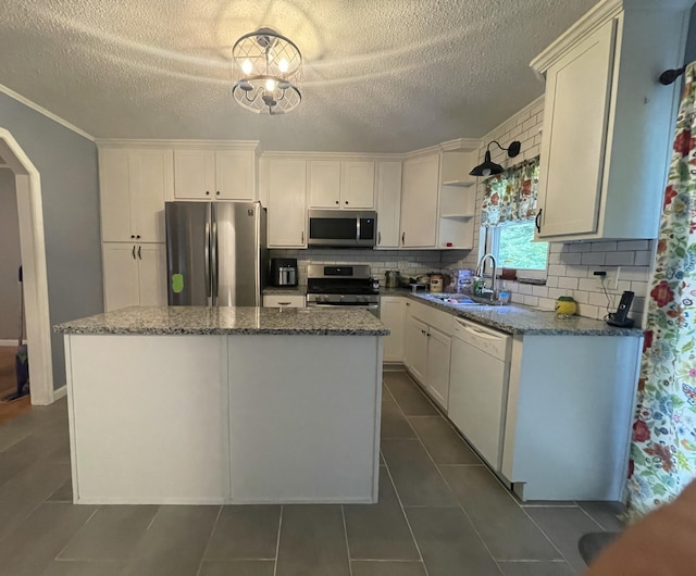 kitchen with white cabinetry, sink, tasteful backsplash, a kitchen island, and appliances with stainless steel finishes