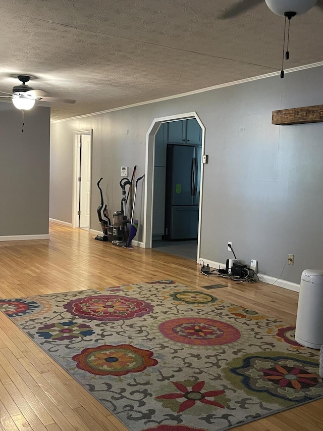 interior space featuring ceiling fan, hardwood / wood-style floors, a textured ceiling, and ornamental molding