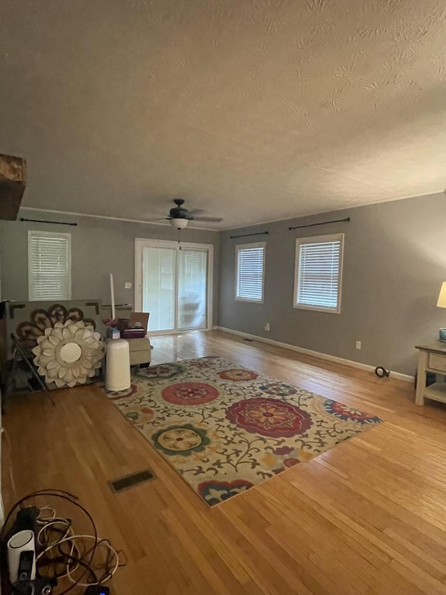 unfurnished living room with ceiling fan, light wood-type flooring, and a textured ceiling