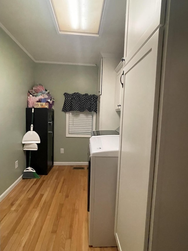 laundry room with cabinets, light wood-type flooring, and separate washer and dryer