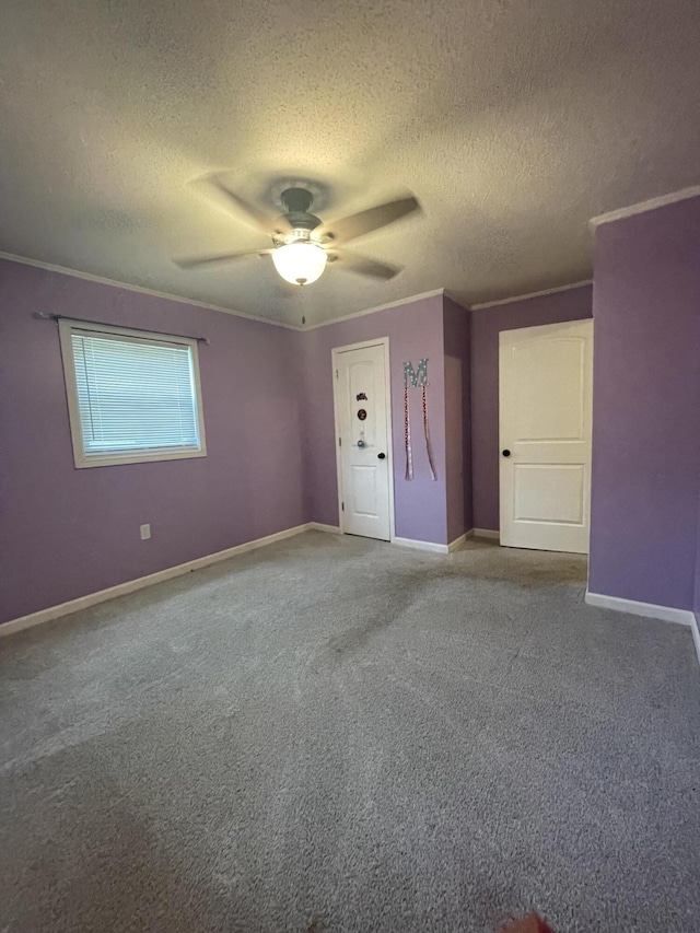 carpeted spare room with a textured ceiling, ceiling fan, and ornamental molding