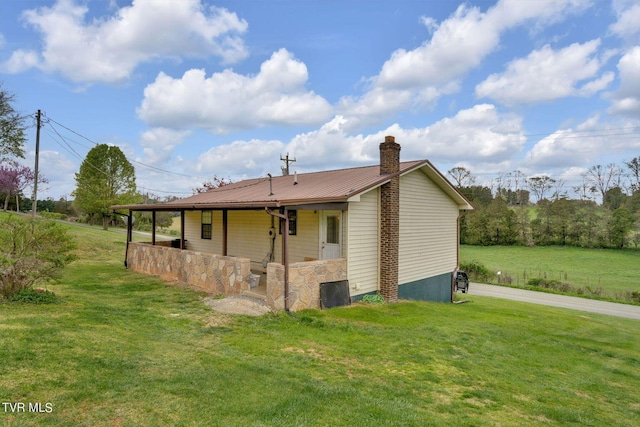 back of property with a lawn, a chimney, and metal roof