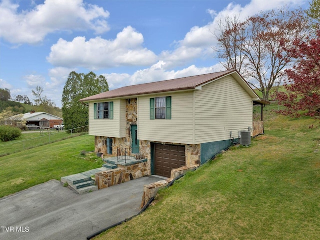 split foyer home with central air condition unit, a front lawn, aphalt driveway, metal roof, and a garage