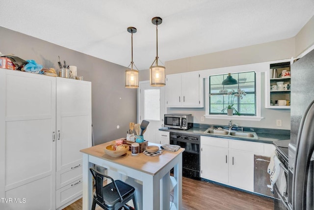kitchen with white cabinets, wood finished floors, stainless steel appliances, and a sink
