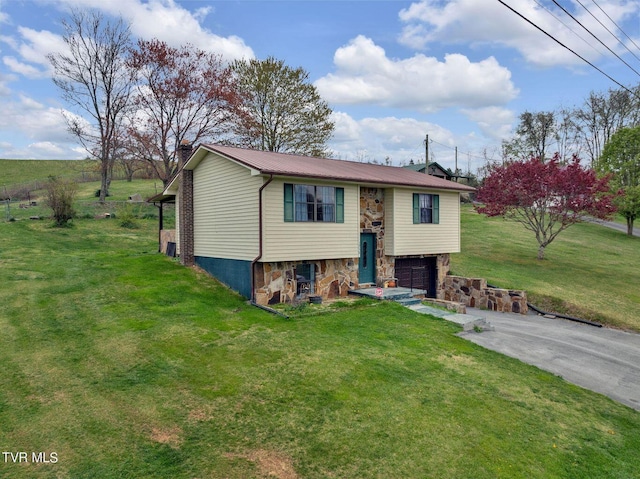 raised ranch with a chimney, metal roof, an attached garage, a front yard, and aphalt driveway