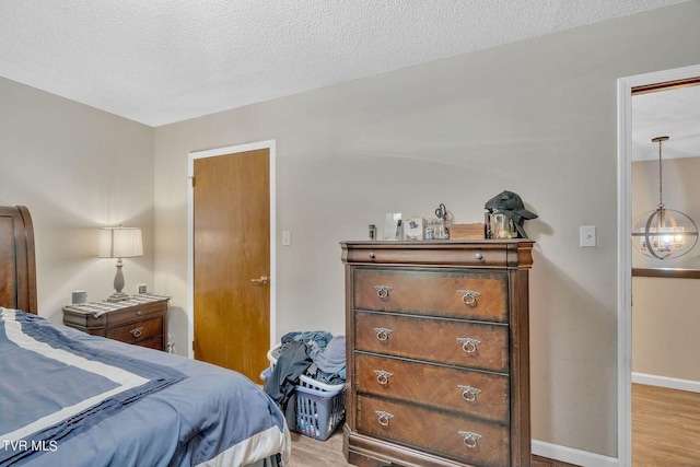 bedroom featuring light wood-type flooring, baseboards, and a textured ceiling