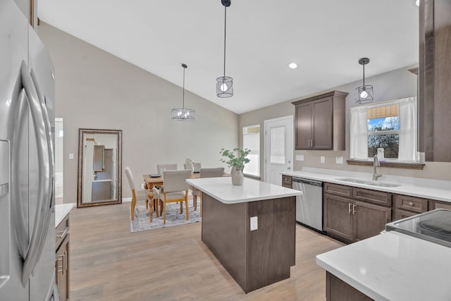 kitchen featuring light wood finished floors, dishwasher, a kitchen island, freestanding refrigerator, and a sink