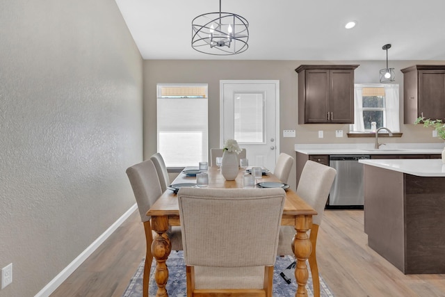 dining space featuring a textured wall, recessed lighting, light wood-style floors, baseboards, and an inviting chandelier