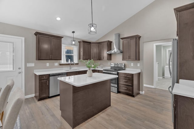 kitchen with appliances with stainless steel finishes, light countertops, dark brown cabinets, wall chimney range hood, and a sink