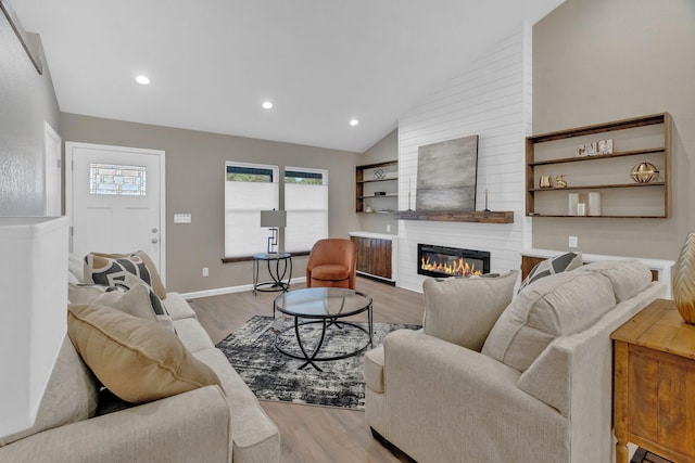 living room with a large fireplace, wood finished floors, lofted ceiling, and recessed lighting