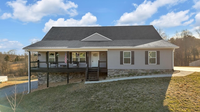 view of front facade with a shingled roof, a porch, and a front yard